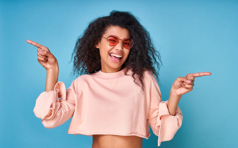 An optimistic light-skinned black girl with fine waves after using styling products for defined curls.