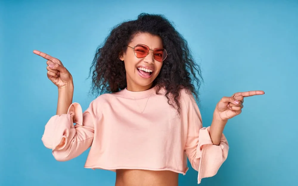 5 Best Products for Fine Wavy Hair: Shampoo, Oil, Gel, & More 7 An optimistic light-skinned black girl with fine waves after using styling products for defined curls.