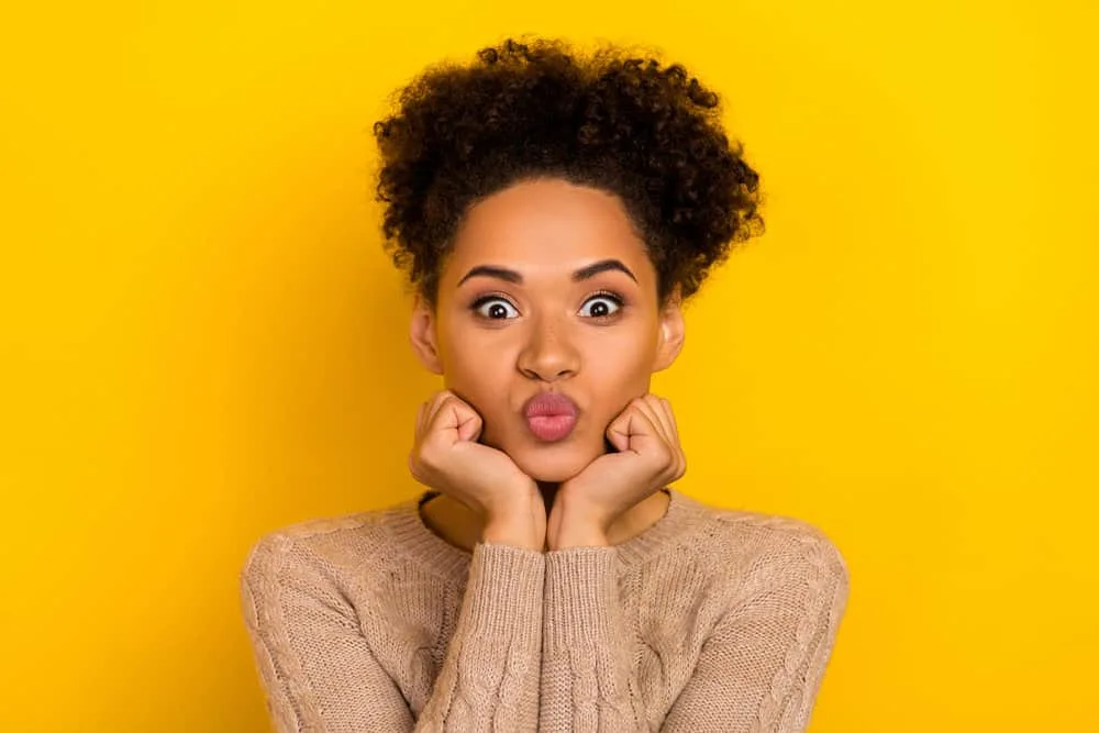 Why Does My Hair Grow Uneven? How to Fix Uneven Hair at Home 7 A black girl makes a kissing face with improving hair health after following Curly Girl Method step-by-step.