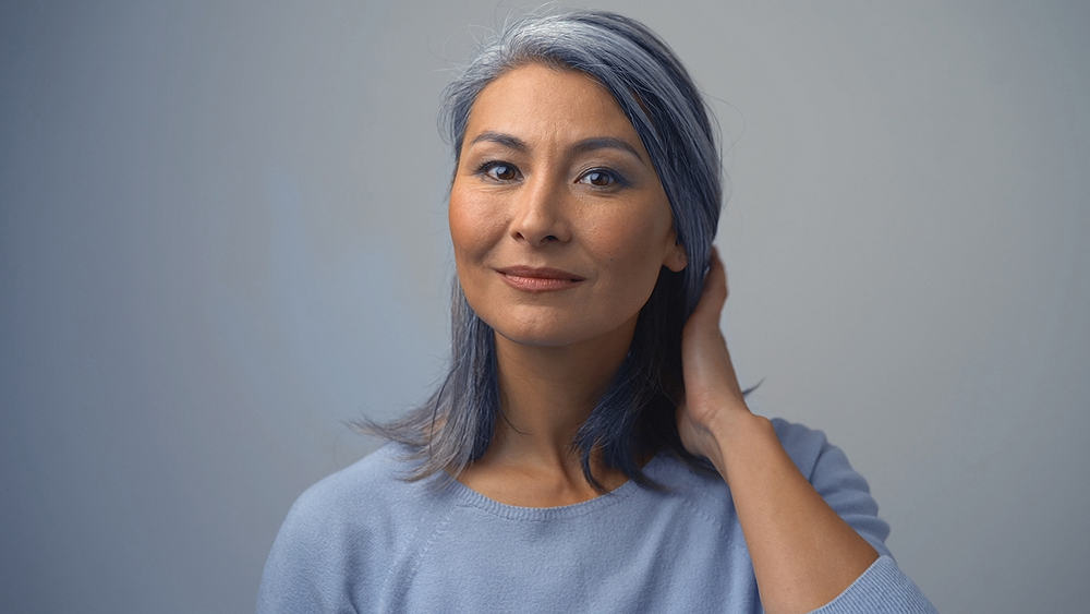 Elderly Asian woman with salt and pepper hair wearing a light blue sweater.