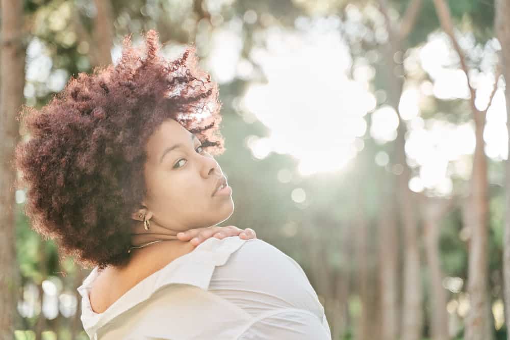 A young lady wearing a copper-color demi-permanent dye on virgin hair with bouncy natural curls.