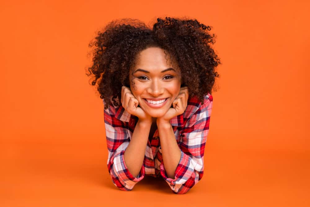 The black woman in the photo has lovely light brown hair after applying semi-permanent dye to her curls.