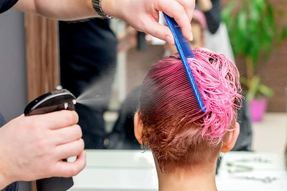 Hairdresser in one of the signature style salons getting a permanent hair color service on thick hair.