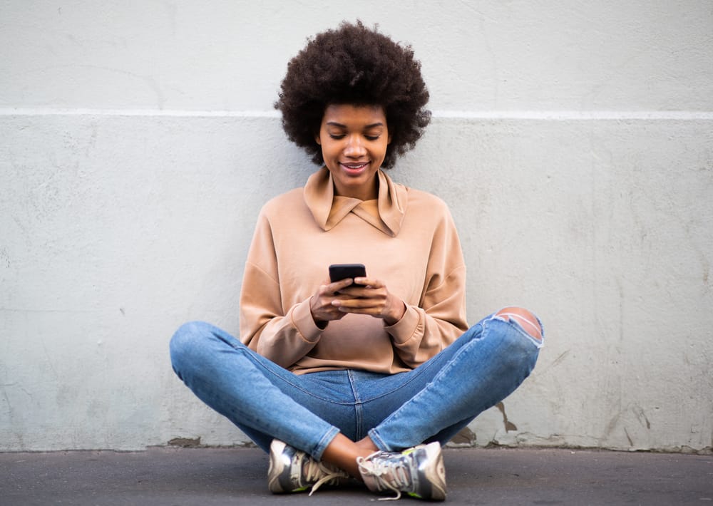 A black female wearing a casual shirt and jeans after air-drying her damp hair and using a moisturizing conditioner.