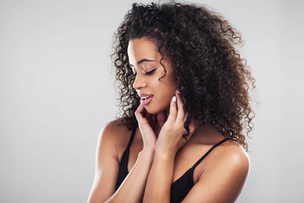 African American woman with thin hair has made her coarser hair strands look thicker using a boar bristle brush.