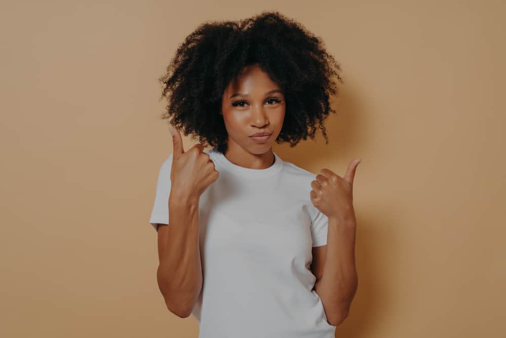 Confident young African female with frizzy hair giving a thumbs-up symbol.