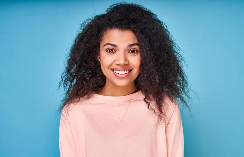 A cute young black girl with beachy waves after using a lightweight treatment for conditioning fine wavy hair.