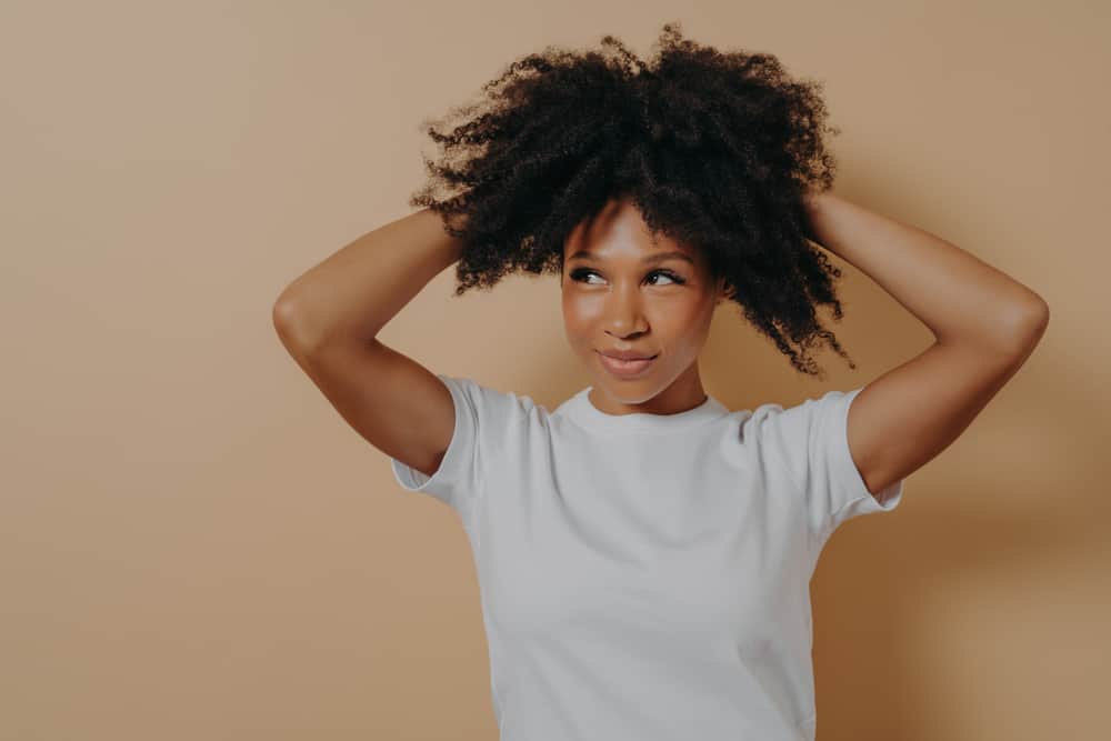 Attractive young woman holding her hair upwards to make her hair curl inward instead of outwards.