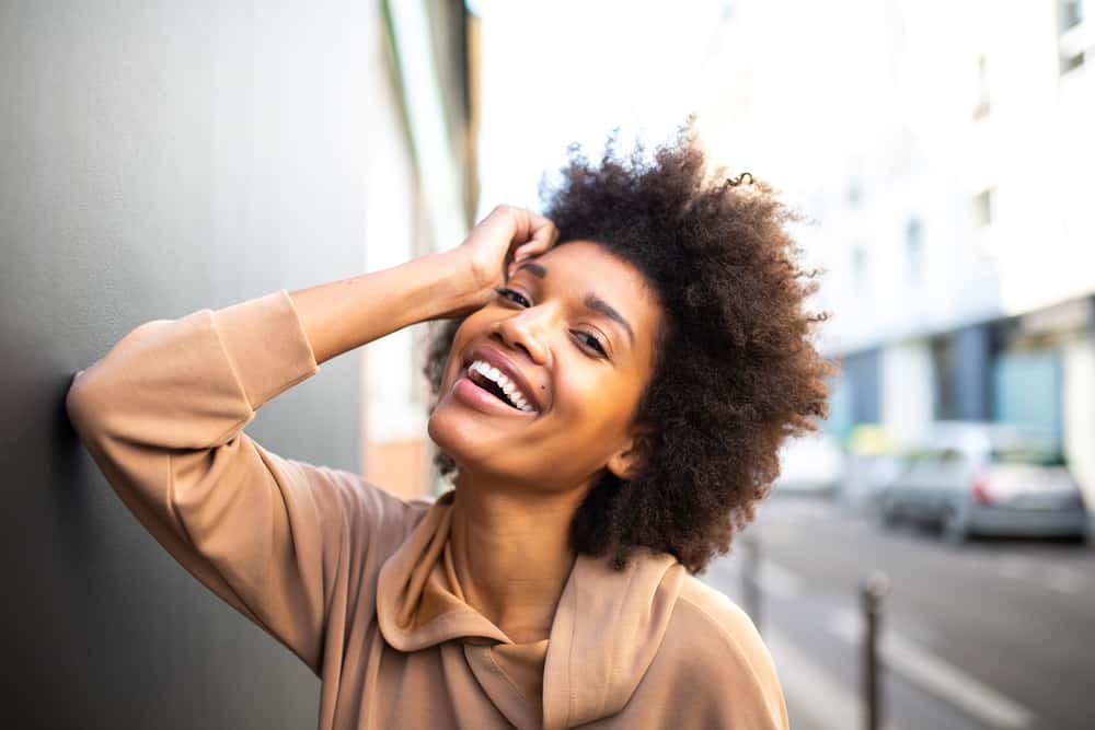 A cute African American female with a 4C hair texture has her loose hairs blowing in the wind.