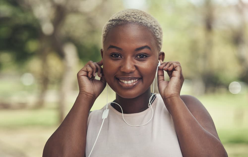 Young African American woman wearing a kinky afro while listening to her Apple earbuds.