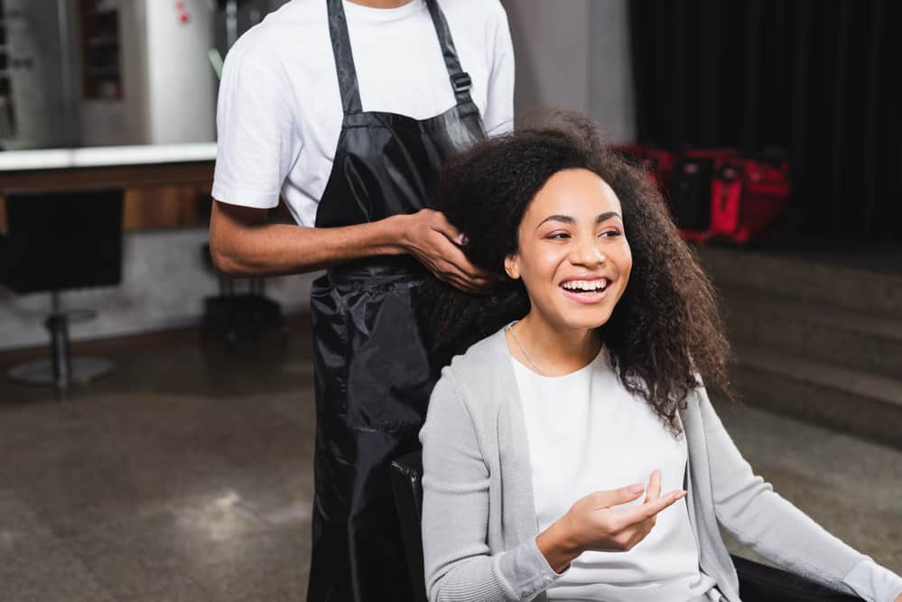 African American female using Regis Salon services to get a shampoo and conditioner service.