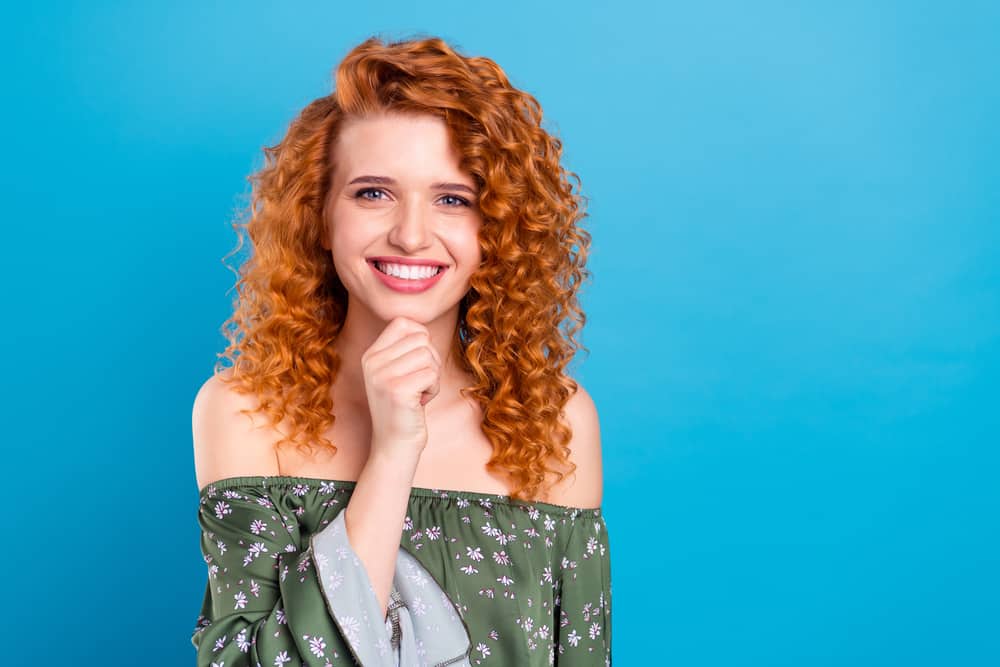 Pretty young lady with dark hair wearing her curly hair red after using hair dye to create a dramatic change.