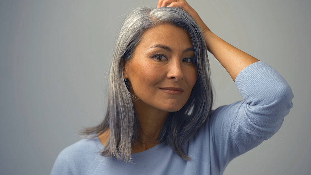 Middle-aged Asian female with natural gray hair follicles that were covered up with permanent hair dye.
