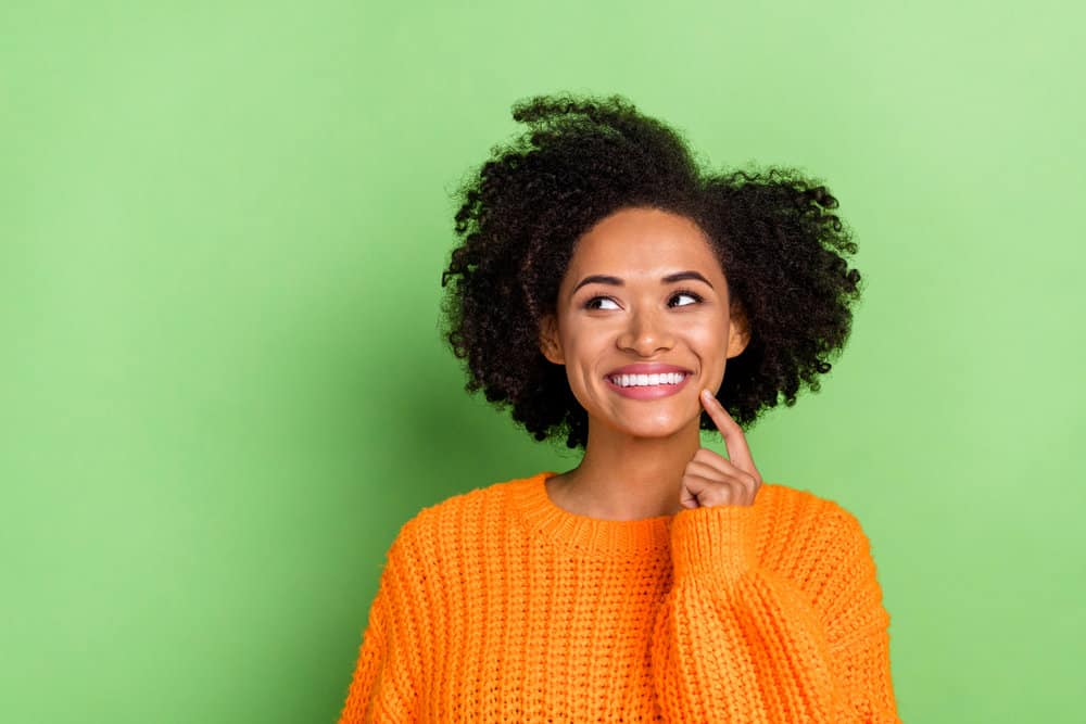 Sweet young black girl wearing a curly hairdo with lighter hair after using light brown hair dye on her black hair.