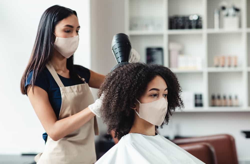 Professional hairdresser using high-quality products on an African American client in a Walmart hair salon.