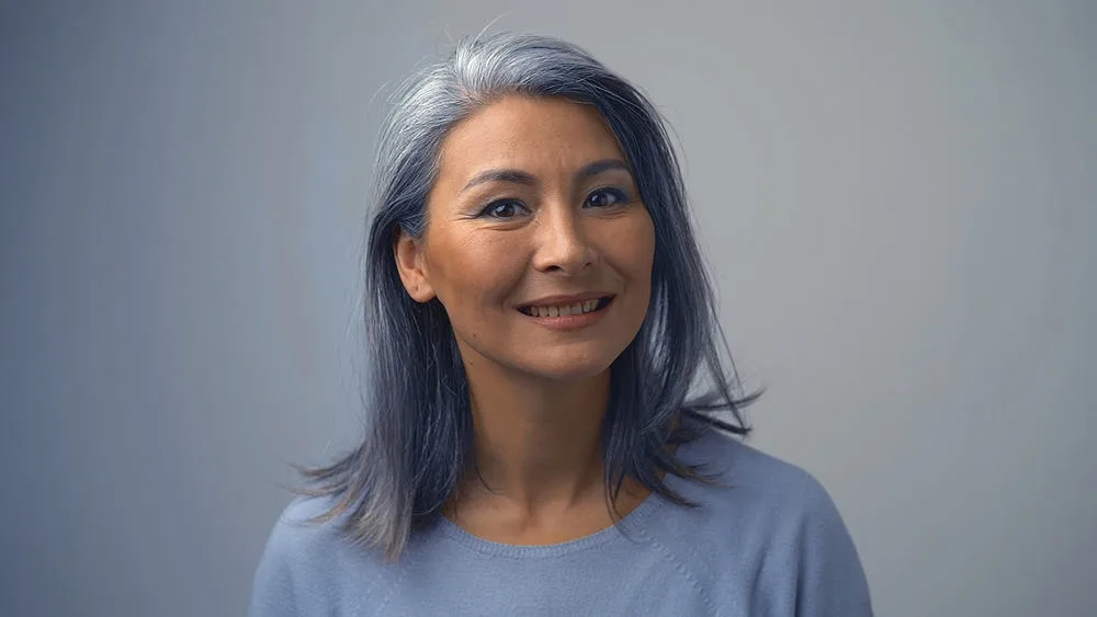 Removing Hair Color to Go Grey at Home: DIY How-to Guide 8 An elderly lady with natural gray hair is smiling after using deep conditioning treatments to repair brittle strands.