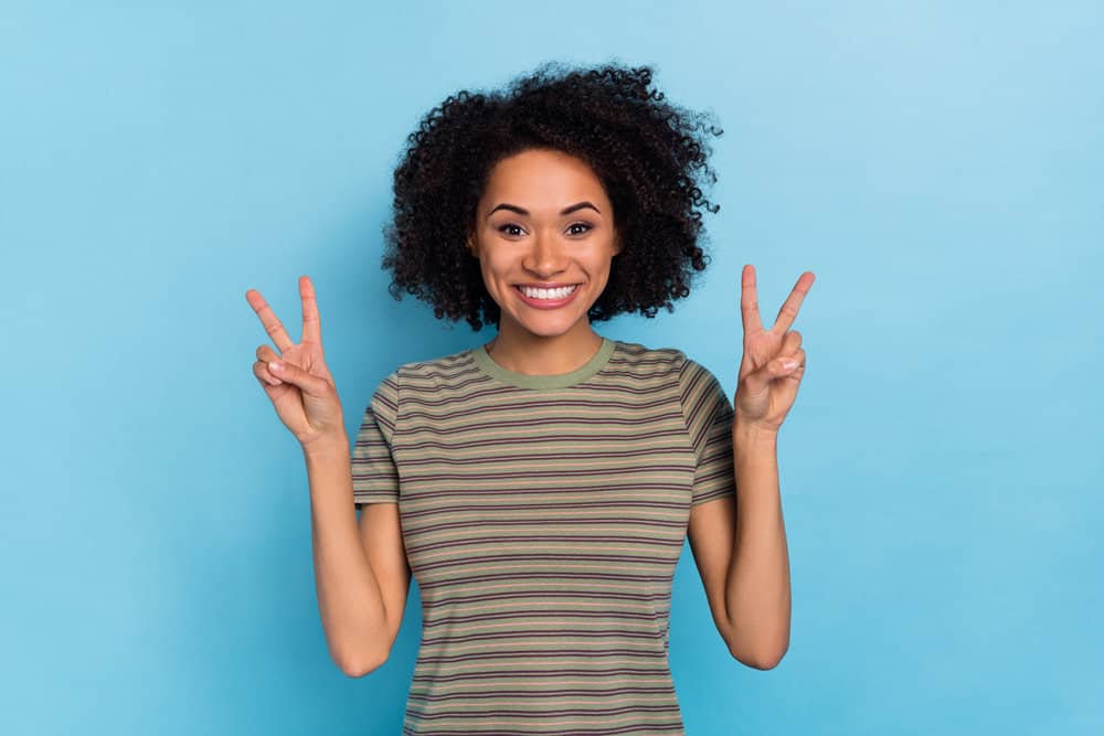 A young African woman after using Curly Girl approved hair products to prevent breakage on her curly hair.