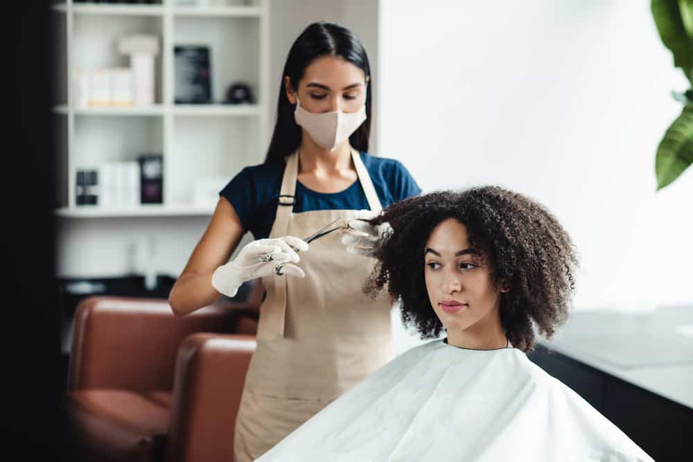 A cute black woman inside a Walmart hair salon gets an express haircut and hair color treatment.