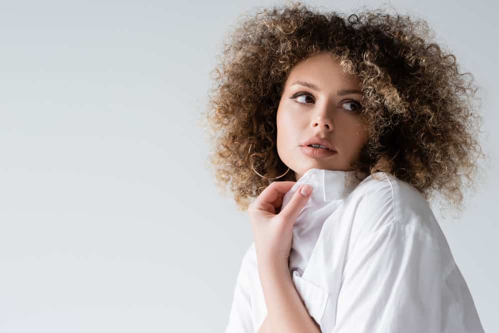 Young white girl with 4C hair after using heated tools to create tight coils on her naturally wavy hair texture.