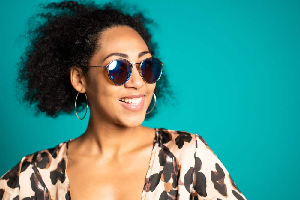 African American lady after cutting her own hair follicles is wearing her hair in a pinned-up hairstyle.