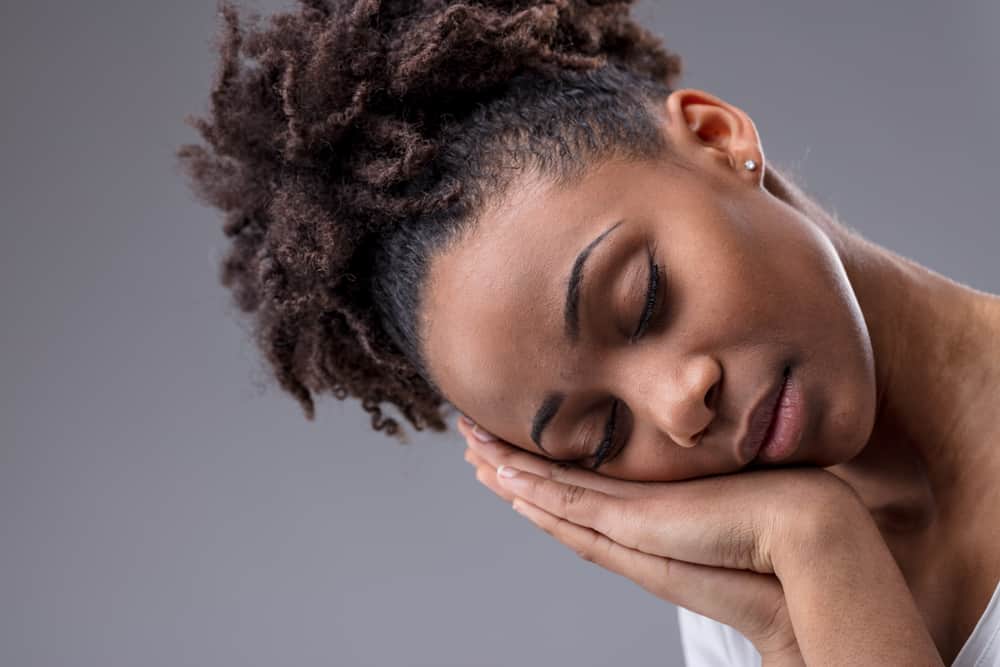 Tired black female with light hair tips and dark brown hair underneath getting a new hairdo from her hair stylist.