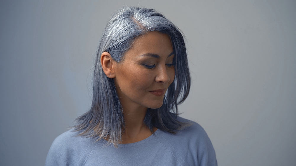 Beautiful senior female with natural grey hair showing off her hair after removing permanent hair dye.