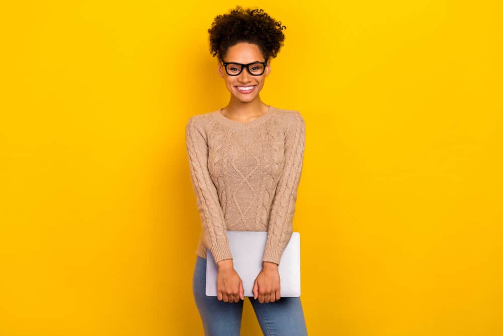 A young girl with a curly pineapple updo that can be worn on different hair types and styled with various hair products.