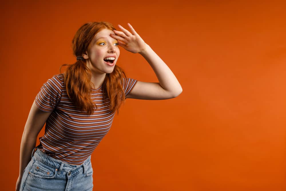 Cute lady with 2A straight brassy hair wearing her dark locks in a pigtail hairstyle while looking to the distance.