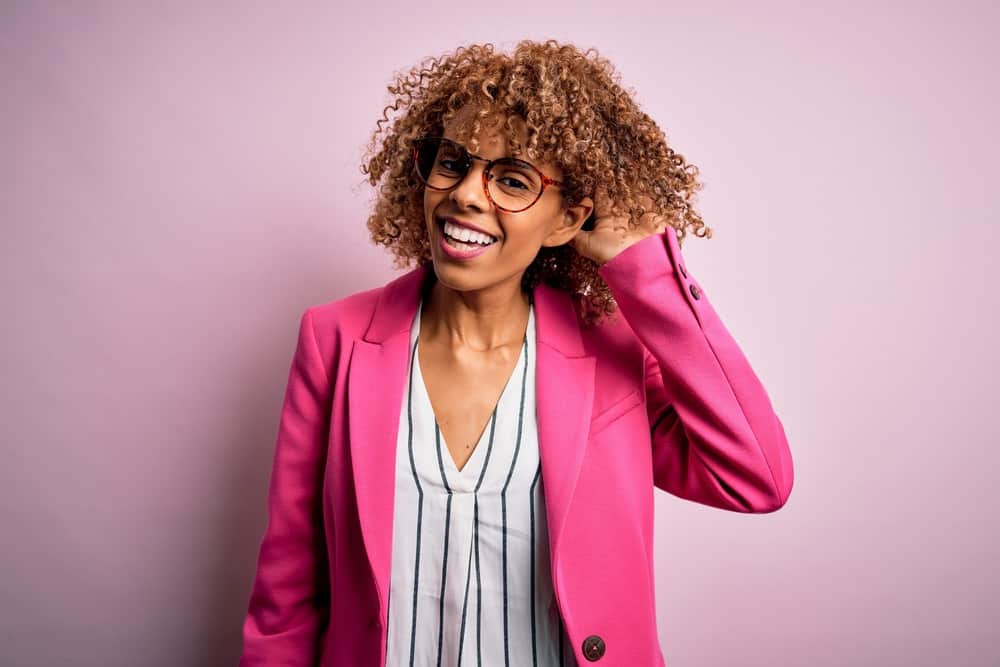 Young black woman with healthy hair showing off her beautiful curls colored with plant-based dye.