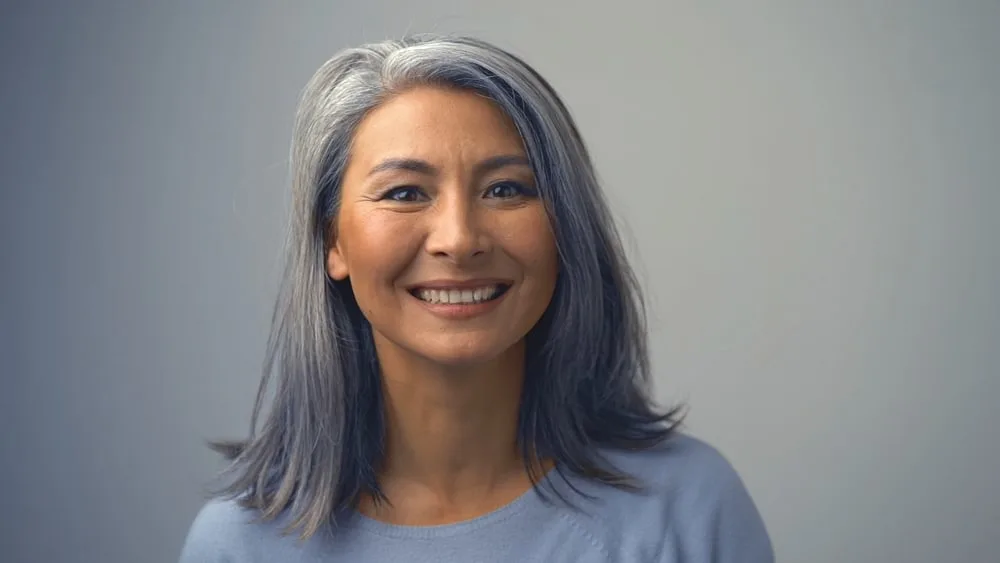 Removing Hair Color to Go Grey at Home: DIY How-to Guide 12 A young woman with a dark head of hair and red lipstick is seen wearing subtle make-up.
