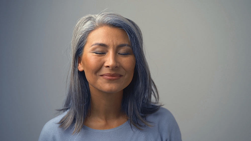 A charming Asian lady with her hair dyed is wanting to remove permanent hair dye to show off her silver hair.