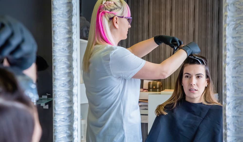 Beautiful young woman getting hair trimmed at Great Clips after ordering a standard adult haircut.