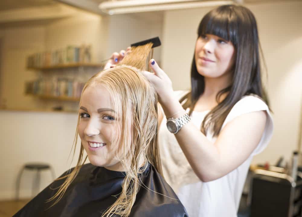 Stylist during a women's hair with a full foil balayage after a finishing shampoo and style finish.