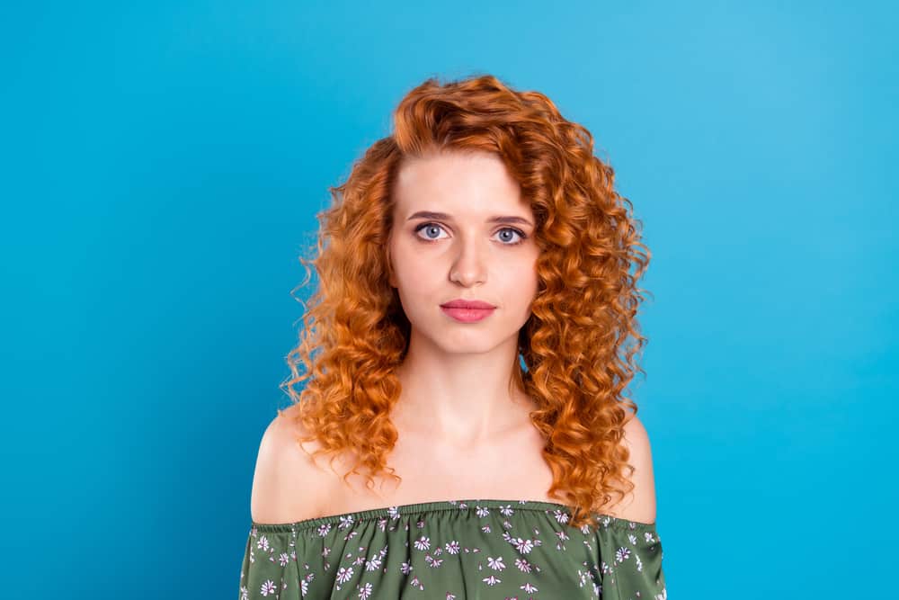 A young white girl with curly orange hair lightened her hair after putting blonde dye on her curls.