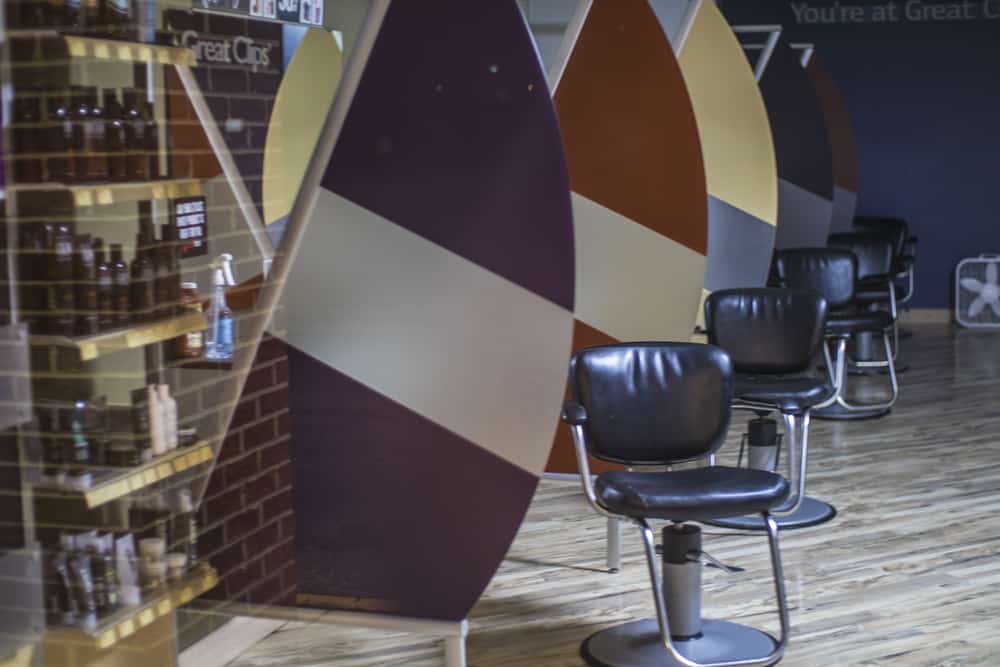 Row of barber chairs inside inside of the salon, with the Great Clips haircut price shown on the left.