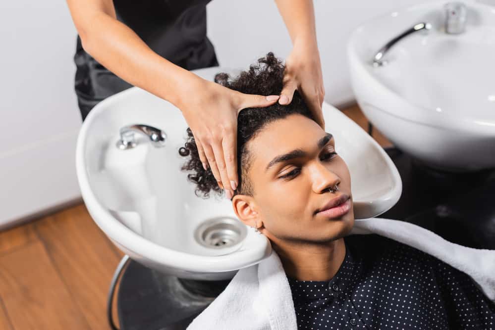 Lady washing a customer's hair in the Sola Salon Suite, where she's started her own salon business.