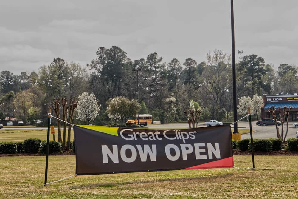 Great Clips hair salon street banner encouraging on-site visits in addition to using the online check-in app.