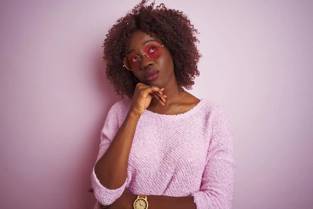 Weaves vs Wigs Debated: Which Is Better a Wig or Weave? 7 Thoughtful young black girl wearing dark brown hair color to cover up damaged strands from heat styling.