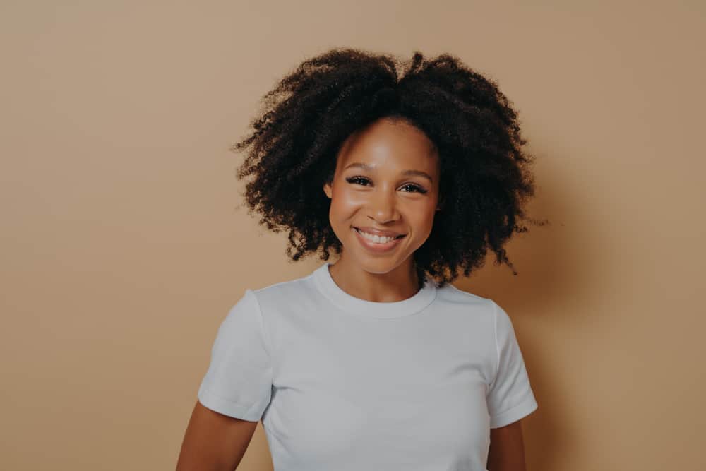 Young African American female whose wavy hair curls at then ends wearing a casual white t-shirt.