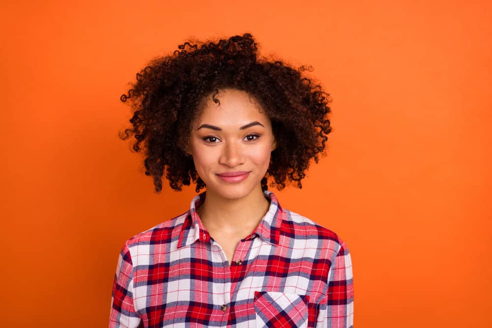 Young black lady with dark brown hair follicles after using a DIY hair coloring kit to dye her hair naturally.