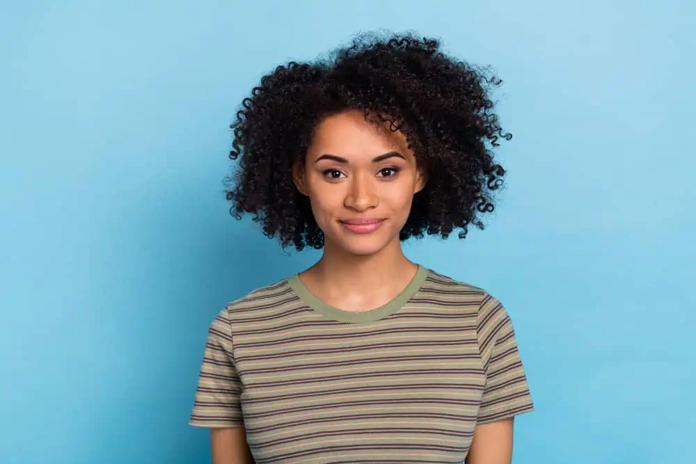 Why Is My Hair Getting Shorter Without Cutting It? 1 Cute African American female with healthy hair growth wearing hair extensions on her fine hair to create fullness.