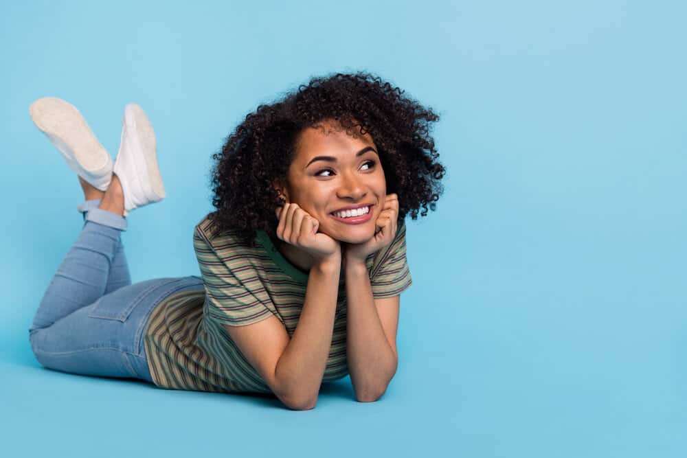 A positive young lady wearing casual clothes with new hair growth after she stopped using heat tools (e.g., curling iron).