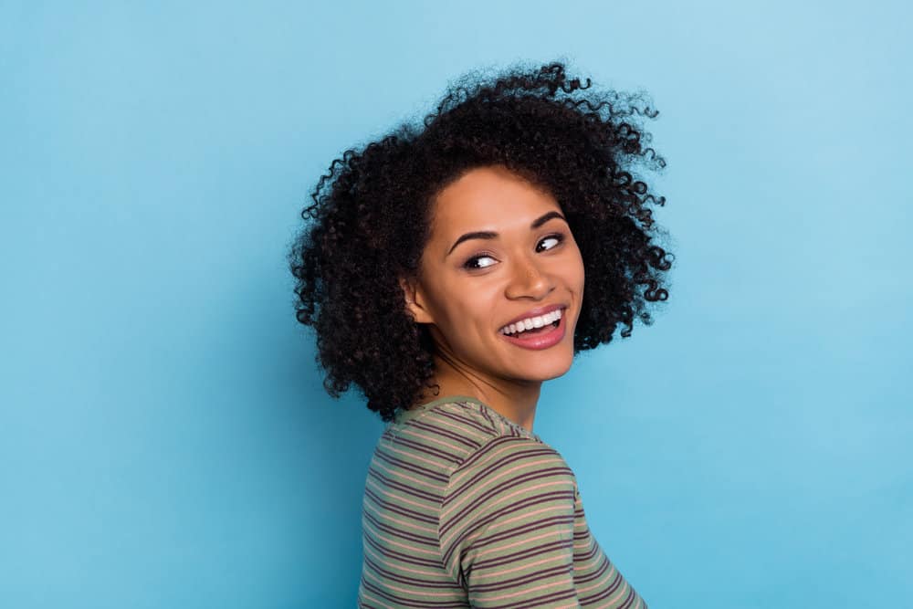 Cheerful young black girl with mild hair damage after using a chemical relaxer on her naturally curly hair.