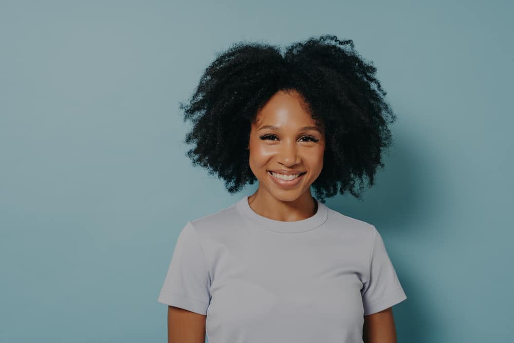 Smiling African American female wearing a wash and go showing how her hair grows outwards.