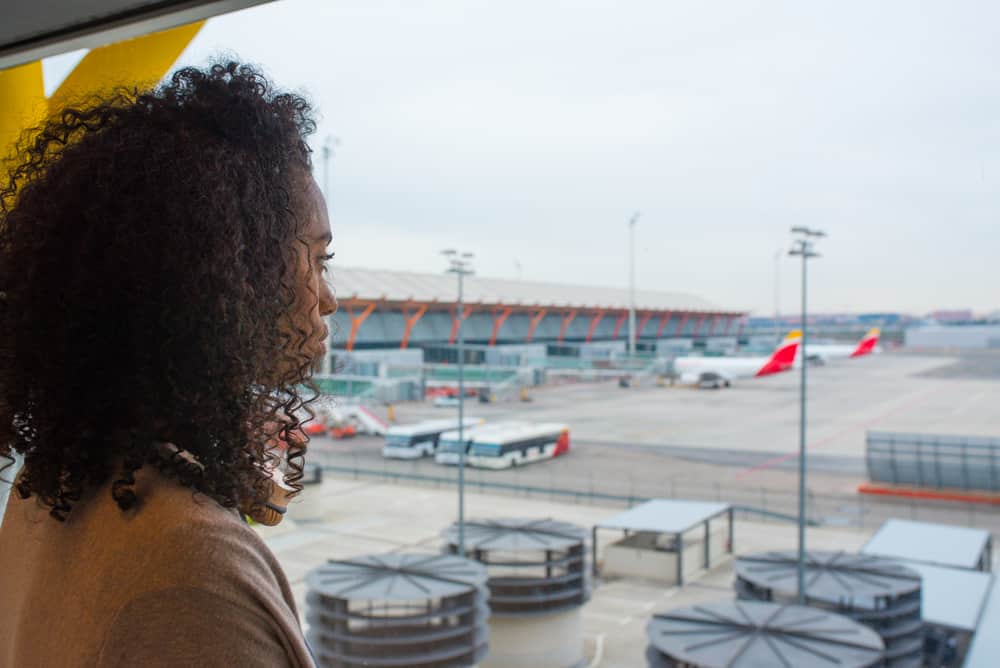 A black lady with hair mousse, shaving cream, spray deodorant and pump hairspray in her carry-on luggage.