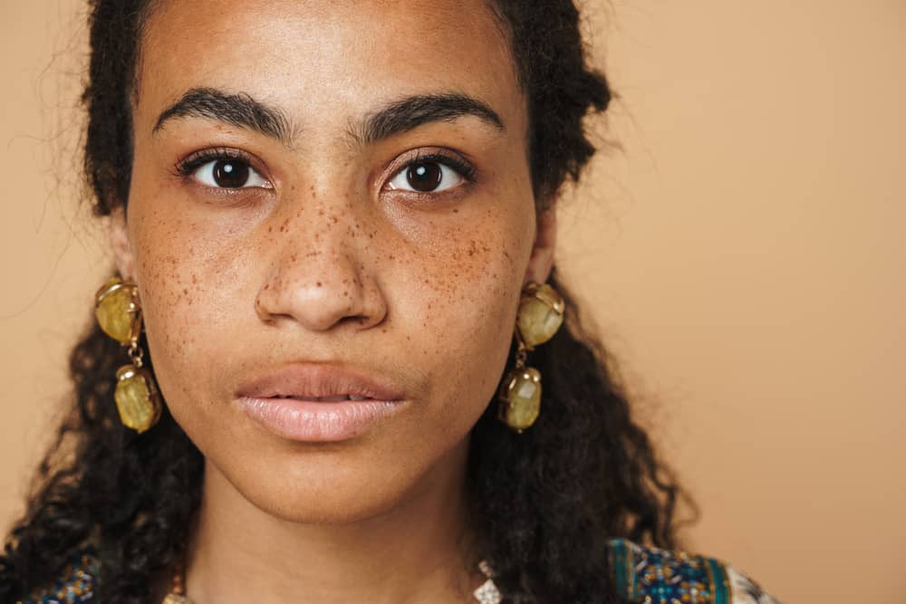 Young African American woman with brassy tones on her dark brown hair after using purple conditioner.