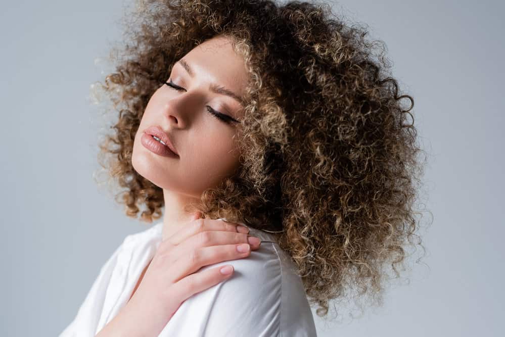 A white woman with tightly curled 4a hair that resembles afro-textured hair found in other ethnicities.