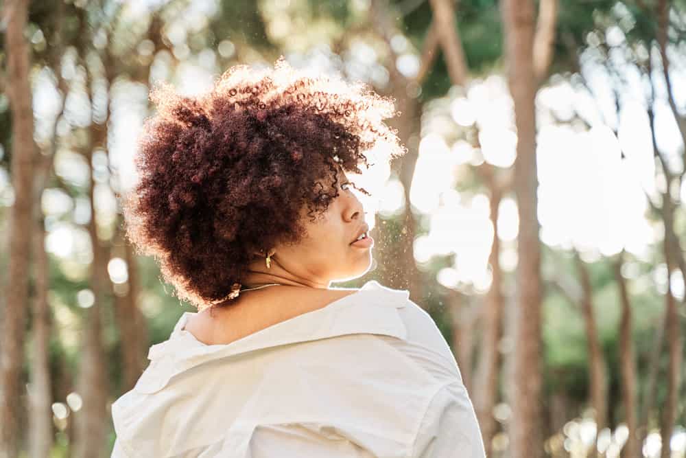 Young black woman with red and pink hair dyed with semi-permanent dye by a professional hair colorist.