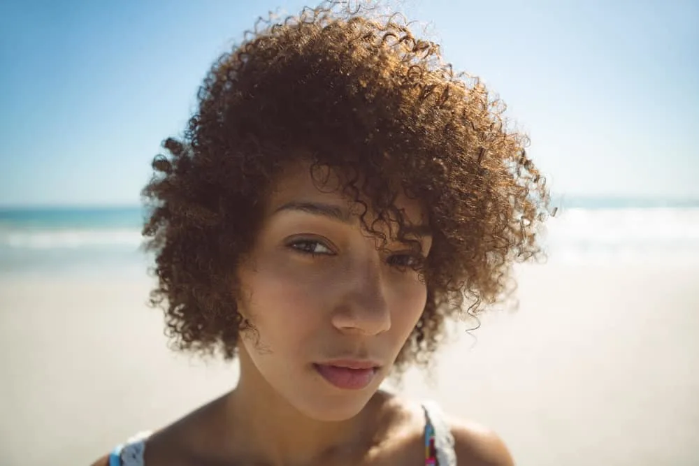 A black woman wearing her hair wavy after letting it air dry during a trip to the beach during vacation.