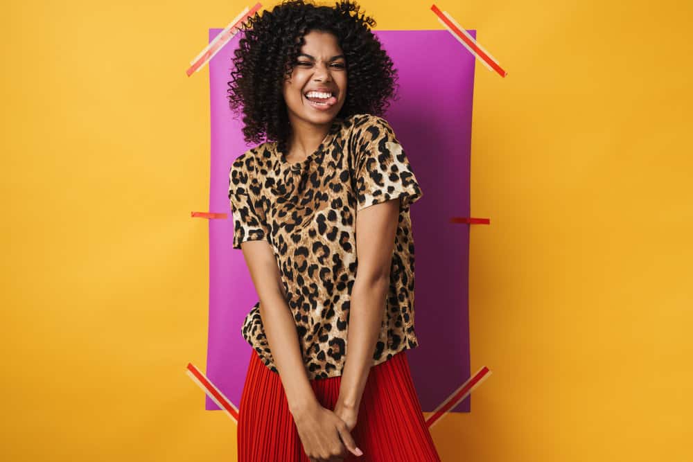 African American female with light brown curls wearing an animal print shirt after styling her hair with a hair mask.
